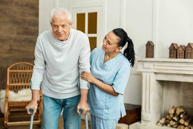 Caregiver helping elderly man walk